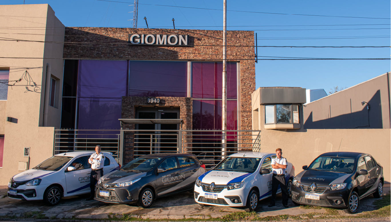 Imagen de frente de la oficina de Giomond. Se ven autos estacionados y 2 empleados